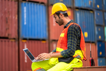 Wall Mural - Professional engineer container cargo foreman in helmets working and using laptop checking stock into container for loading.logistic transport and business industry export