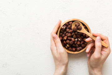 Woman hands holding a wooden bowl with hazelnut nuts. Healthy food and snack. Vegetarian snacks of different nuts