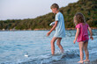 © Vladyslav - Brother and sister are playing on the beach. A girl and a boy are playing with homemade boats in sea water. Children splash in the Adriatic Sea.