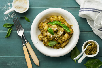 Potato gnocchi. Traditional homemade potato gnocchi with sauce pesto, kitchen table and basil on old rustic turquoise kitchen table. Traditional Italian food. Traditional Italian food. Top view.