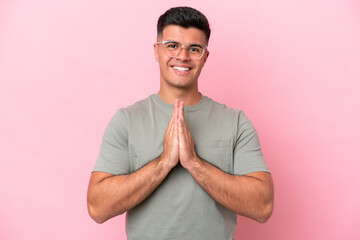 Poster - Young caucasian handsome man isolated on pink background keeps palm together. Person asks for something