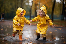 Happy Smiling Children In Yellow Raincoat And Rain Boots Running In Puddle An Autumn Walk