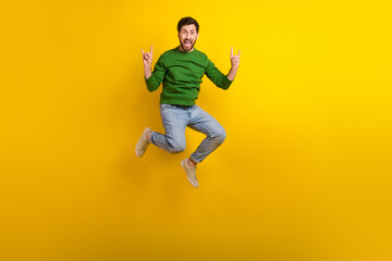 Poster - Full size body photo of jump trampoline crazy guy fingers showing rock roll punk gesturing singing isolated on yellow color background