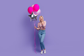 Sticker - Full body portrait of astonished cheerful lady hand touch cheek hold air balloons empty space isolated on purple color background