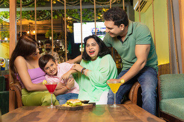 Poster - Indian family giving happy expression at restaurant.