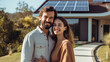 Smiling couple in their 30s standing in the driveway of a large house with solar panels installed