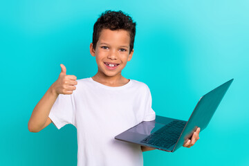 Portrait of funny positive preteen age boy brown hair stylish clothes thumb up remote online shop isolated on cyan color background