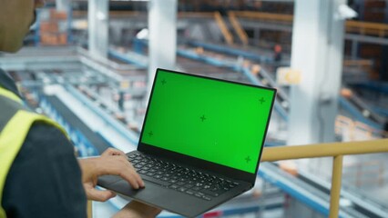 Male Employee Working at Modern Logistics Center With Conveyor Belt. International Online Shopping Business Facility. Caucasian Man Using Laptop Computer with a Green Screen Chromakey Mock Up Display.