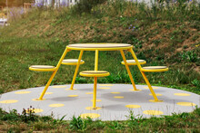Picnic Table Gazebo On Nature Background. Yellow Metal Public Patio Furniture Round Table With Chairs In City Park Or Lounging Area.