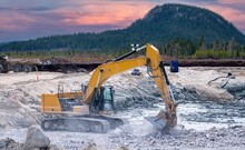 Yellow Excavator Working On A Construction Site In The Taiga At Sunset