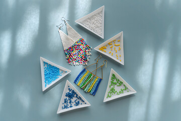 Wall Mural - Triangular bead trays with beaded earrings. Different colored seed beads in containers for needlework and beading. Creativity and  hobby concept