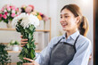 © Katcha - Female florist in apron holding white chrysanthemum with enjoying to creating and designing floral for