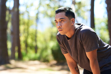 Tired and sweaty Asian man takes a break while trail running, breathing