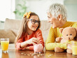 © Lumos sp - child money saving grandfmother family coin senior finance bank piggybank happy investment granddaughter girl financial elderly cash