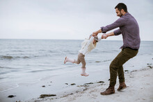 Father And Daughter Playing On A Beach During Winter