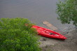A red kayak on the river bank
