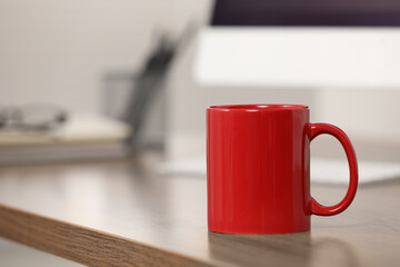 Poster - Red ceramic mug on wooden table at workplace. Space for text