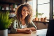 © Adriana - Young smiling businesswoman sitting at her desk in a light-filled modern office