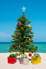 Christmas Tree on the beach. Merry Christmas. Present gift box. Happy New Year. Winter Holidays. Miami Florida vacation. Decorated Christmas pine or fir tree. Tropical Nature. Blue ocean on background