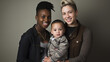 © Domingo - two lesbian mothers, one black woman and other white latina genderless with an adopted child isolated over a dark background. studio photo of LGBTIQ+ about adoption and modern families