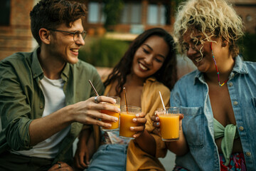 Wall Mural - Loving diverse friends sitting, drinking, and talking at the backyard party.