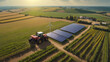 Aerial view captures the expansive farmland, adorned with a tractor navigating through the rows of crops, while solar cells gleam under the sun's embrace.