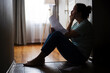 © spyrakot - Silhouette of sad and depressed woman sitting on the floor at home