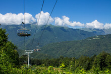 Cable Car Seats Soar Over Beautiful Mountains And Clouds On A Sunny Summer Day In Krasnaya Polyana Sochi Russia