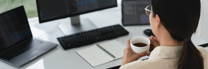Developer programmer drinking coffee and checking code on monitor for programming to developing web