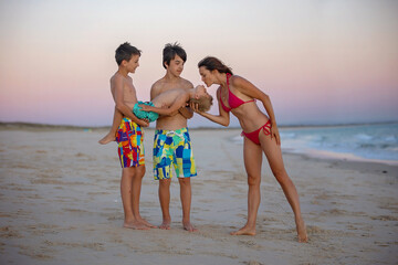 Wall Mural - Happy children, boys, playing on the beach on sunset, kid cover in sand, smiling, laughing