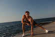 © gstockstudio - Handsome male athlete doing stretching exercises outdoors with the sea on background