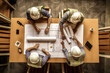 © Marharyta - Three construction workers working on construction drawings and paperwork.