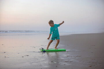 Wall Mural - Happy children, boys, playing on the beach on sunset, kid cover in sand, smiling, laughing