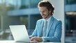 © AdriFerrer - Cheerful businessman using laptop in a bright office environment.
