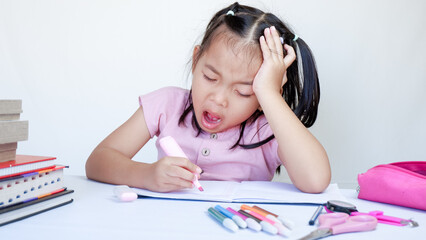 Wall Mural - Portrait Of Sleepy Little Asian Female Child At Desk Tired After Doing School Homework.