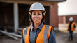 © Prasanth - woman working on a construction site, construction hard hat and work vest, smirking, middle aged or older
