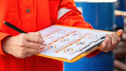 Wall Mural - action of safety officer is using a pen to checking on the hazadous material symbol label form with 