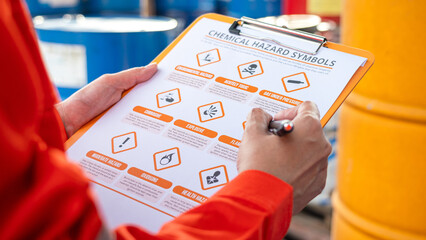 Wall Mural - action of safety officer is using a pen to checking on the hazadous material symbol label form with 