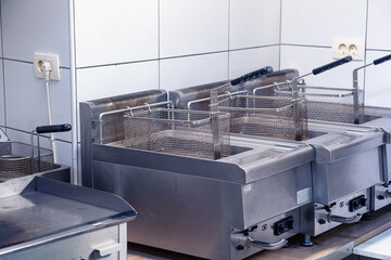 Equipment for deep-frying dishes. Industrial fryers in a restaurant. Stainless steel deep fryers