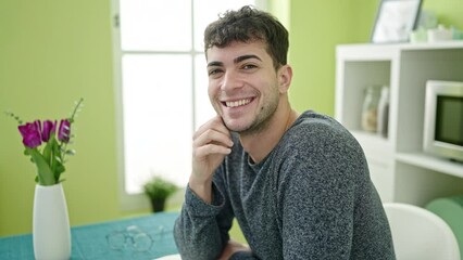 Canvas Print - Young hispanic man smiling confident sitting on the table at dinning room