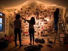 Teenagers Decorating Their New Room's Walls With Posters And Lights