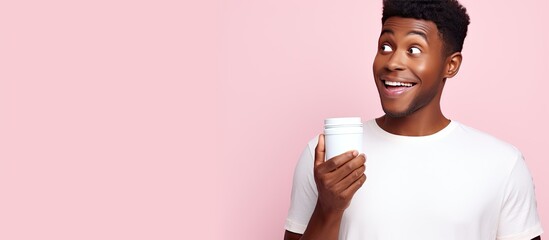 Poster - Enthusiastic young African American man in white polo shirt posing against pastel pink wall background Lifestyle concept with empty space Pointing and