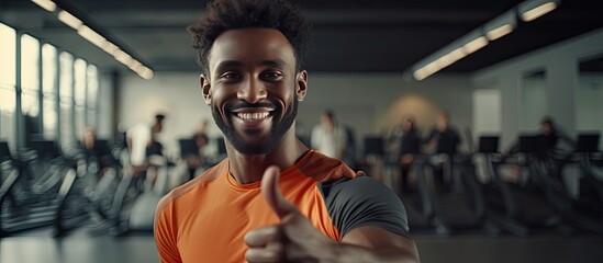 Poster - Happy African man at the gym pointing and smiling wearing sports attire with curly hair