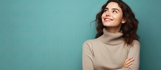 Wall Mural - An attractive young woman full of joy confidence and optimism gazes upwards with her arms crossed