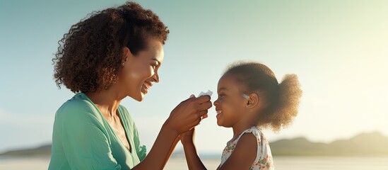 mother applying sunscreen on daughter s nose at beach black woman applying sun lotion on girl s face