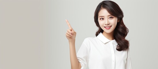 Poster - Smiling Asian woman in white shirt pointing to empty space