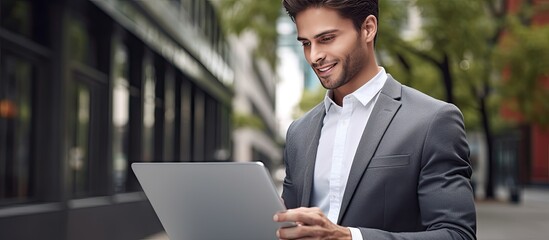 Poster - A young smiling businessman with a laptop isolated on a gray background