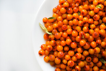 Wall Mural - Orange sea buckthorn berries on a white plate. Hippophae.