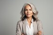 © ChaoticMind - Portrait of confident senior businesswoman, manager, CEO holding arms crossed isolated on gray background, successful business. Attractive gray haired