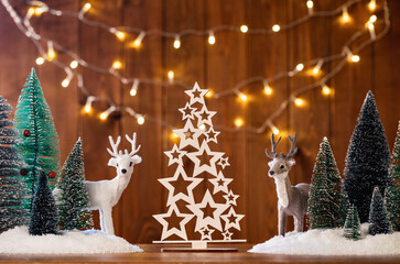 Wall Mural - Mini forest christmas trees with golden lights and two reindeers. Seasons greetings card. Merry Christmas